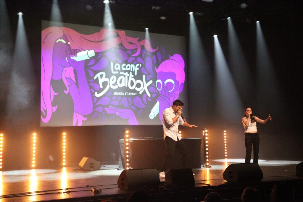 Svent et Julieta en plein spectacle de beatbox sur scène devant un écran affichant le titre La conf' Beatbox